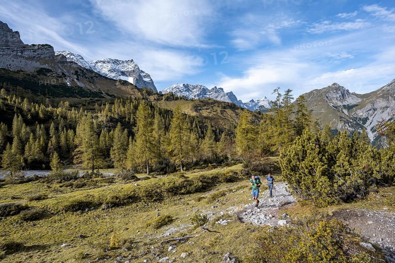 Two mountaineers on a hiking trail, mountain panorama with rocky steep peaks, yellow-coloured larches in autumn, view of the peaks Laliderspitze, Dreizinkenspitze and Spritzkarspitze, hike to the summit of Hahnkampl, Engtal, Karwendel, Tyrol, Austria, Europe