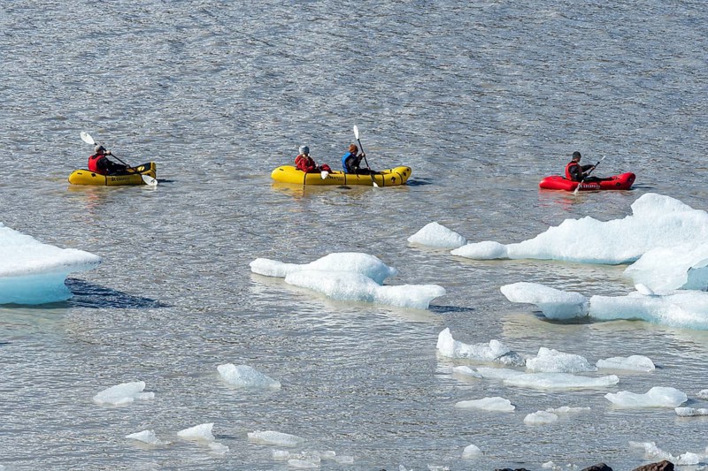 A group of tourists paddles in kayaks between icebergs, glacial lake Fjallsárlón, glacier Fjallsjökull, part of Vatnajökull glacier, Iceland, Europe