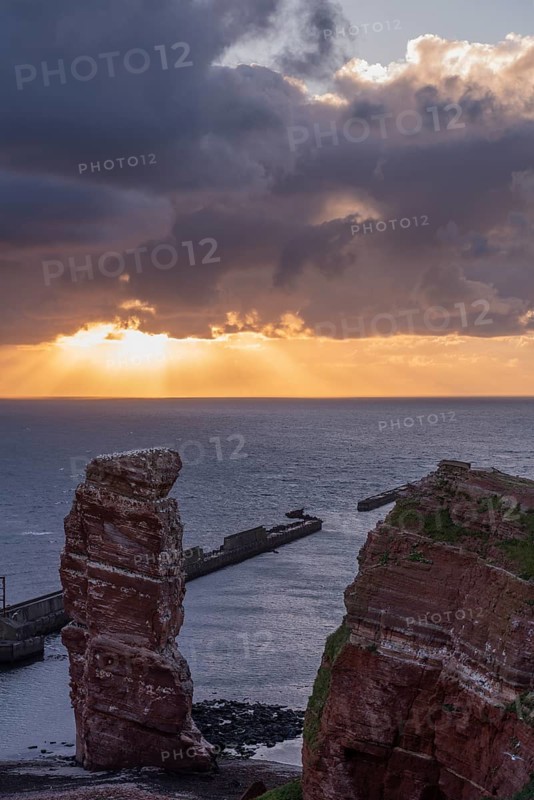 Red sandstone cliff with Lange Anna on the offshore island of Heligoland, mole as protection against erosion, gannets, evening light, cloudy sky, North Sea, Pinneberg district, Schleswig-Holstein, Germany, Europe