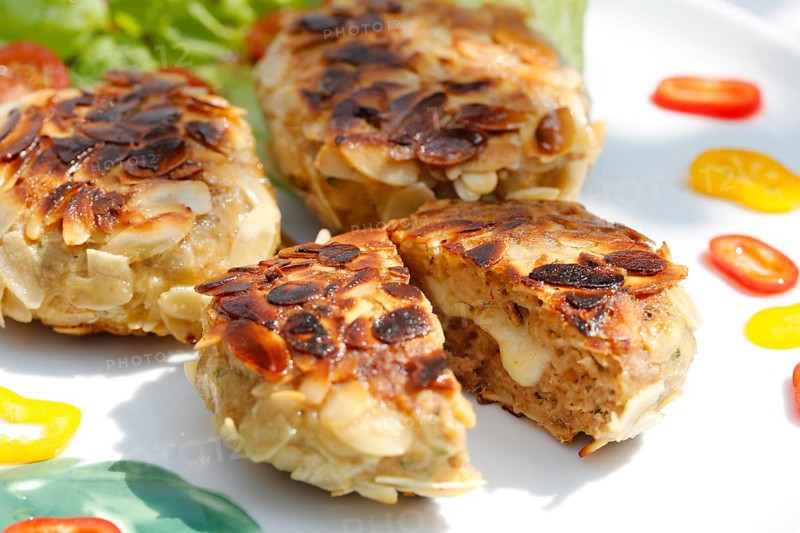 Swabian cuisine, meatballs wrapped in almonds, mixed minced meat, meatballs filled with cheese, fried, meatballs, grandmother's cooking, regional, home cooking, typical Swabian, traditional cuisine reinterpreted, served on a plate with salad, lettuce, cherry tomatoes, cocktail tomatoes, peppers, food photography, studio, Germany, Europe