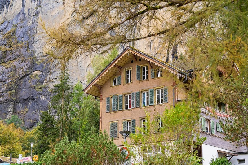 Traditional house in the mountains, surrounded by autumnal trees and a rocky landscape, Lauterbrunnen, Switzerland, Europe