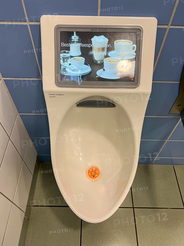 Toilet in a service station, on a motorway, gents, urinal with built-in video monitor, shows commercials
