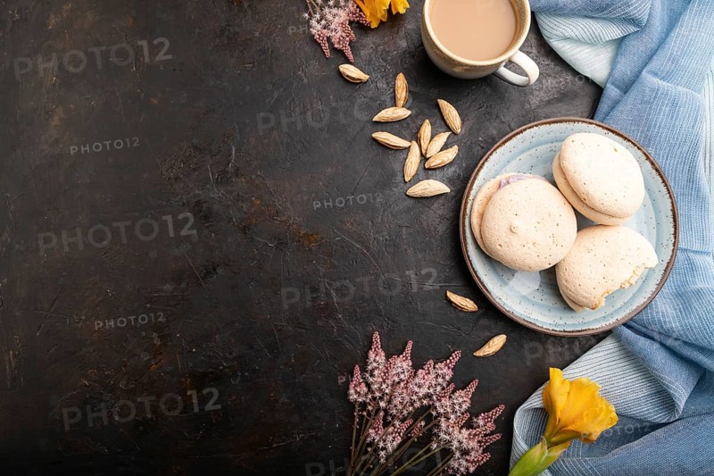 Meringues cakes with cup of coffee on a black concrete background and blue linen textile. Top view, flat lay, copy space