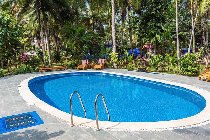 Swimming pool in tropical resort with small garden
