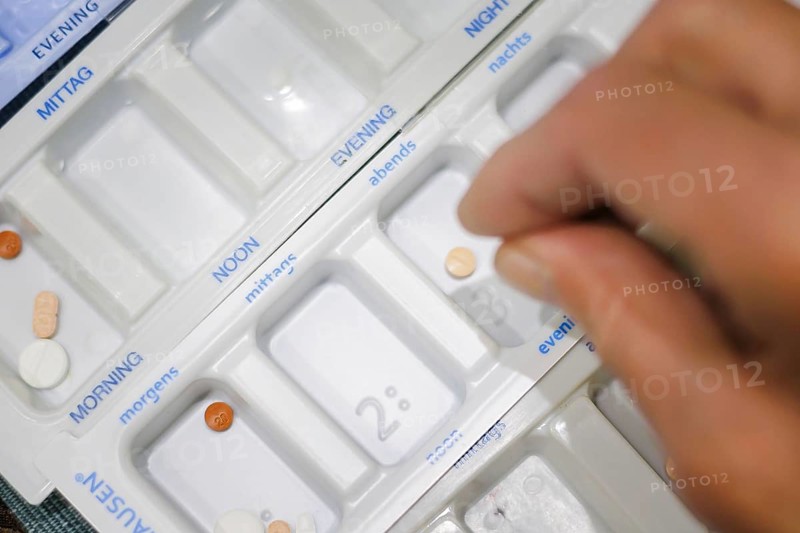 Symbolic photo on the subject of taking medication in old age. Two senior citizens sort various tablets into pill boxes at home to take for the next 16 days. Berlin, 27.07.2024