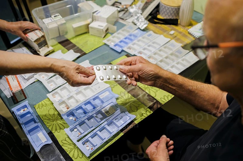 Symbolic photo on the subject of taking medication in old age. Two senior citizens sort various tablets into pill boxes at home to take for the next 16 days. Berlin, 27.07.2024