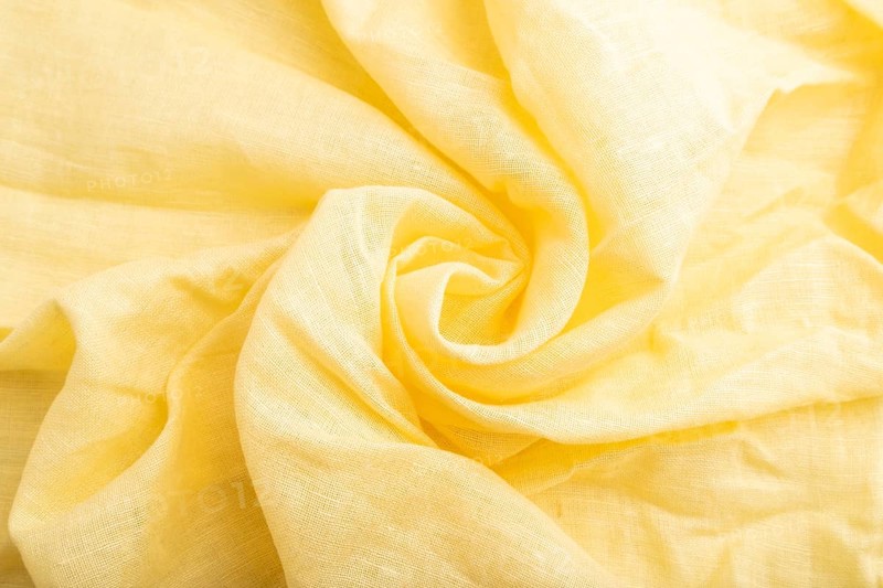 Fragment of yellow linen tissue. Top view, flat lay, natural textile background and texture. wave concept, abstract, spiral form