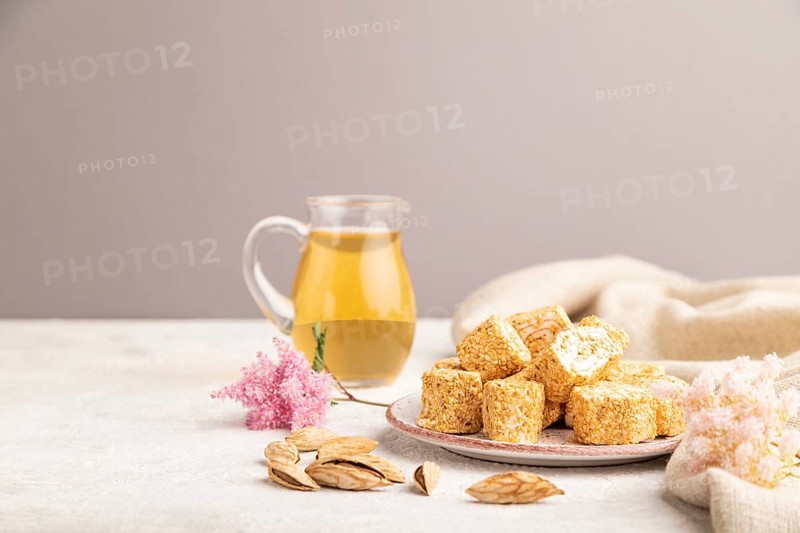 Traditional turkish delight (rahat lokum) with glass of green tea on a gray concrete background and linen textile. side view, copy space