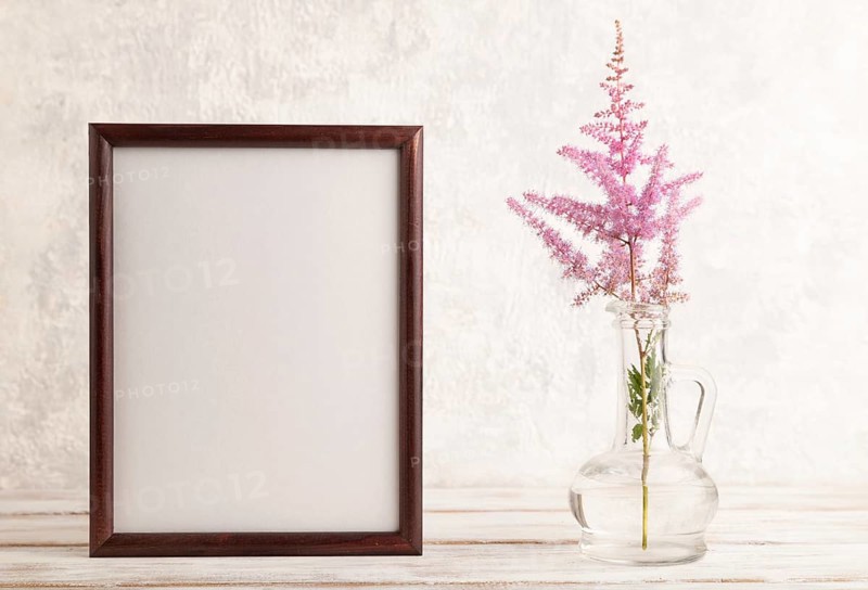Wooden frame with pink astilbe flowers in glass vase on gray concrete background. side view, copy space, still life, mockup, template, spring, summer concept