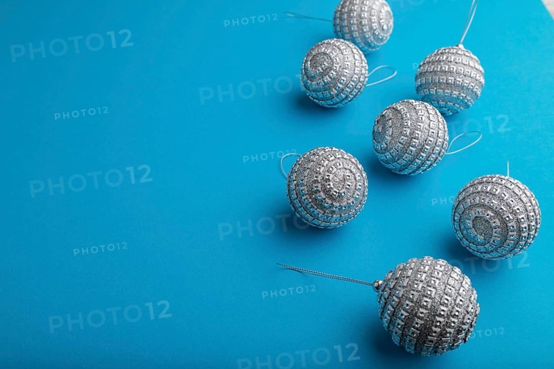 Christmas or New Year composition. Decorations, silver balls, on a blue paper background. Side view, copy space