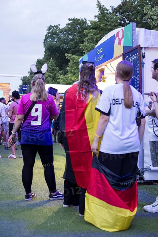 Fans with German flags in front of one of the food stalls in the fan zone at the Brandenburg Tor during the round of 16 match between Germany and Denmark at the European Football Championship, Berlin, 29 June 2024