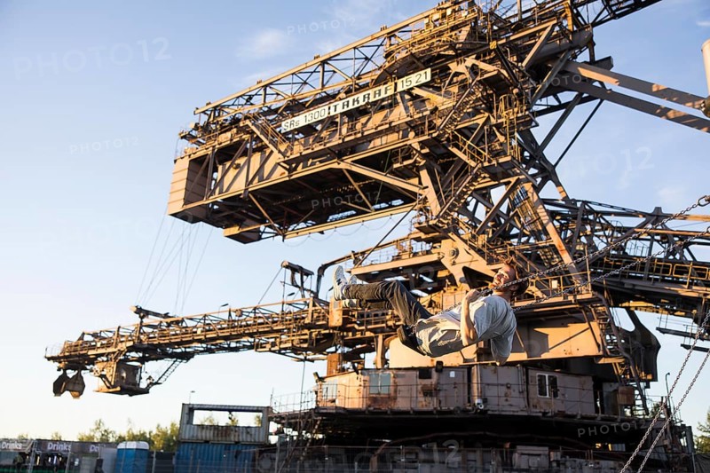 A man swings in front of an open-cast mining excavator illuminated by the evening sun at the Melt Festival in Ferropolis on 13 July 2024. After a total of 27 years, the festival will take place for the last time in 2024