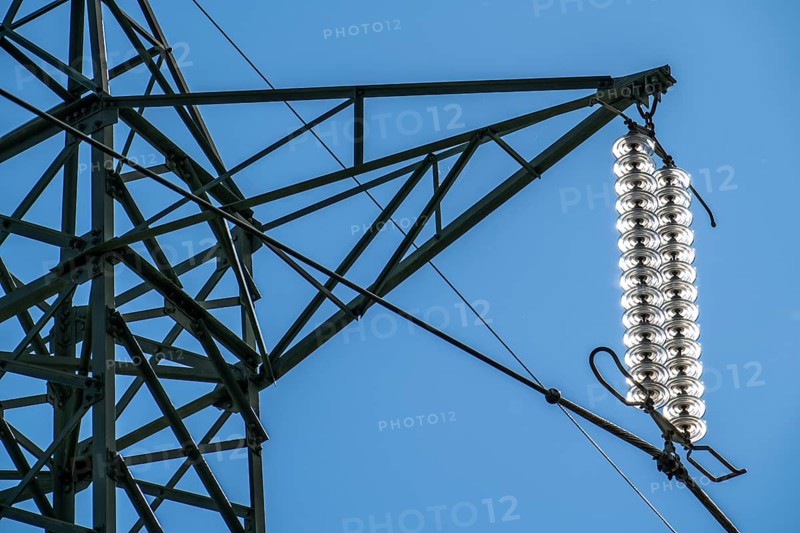 Insulators made of glass on a high-voltage line, they hang on the pylons as a suspension device between the pylon and the live, non-insulated cable, extra-high voltage line, symbolic image energy