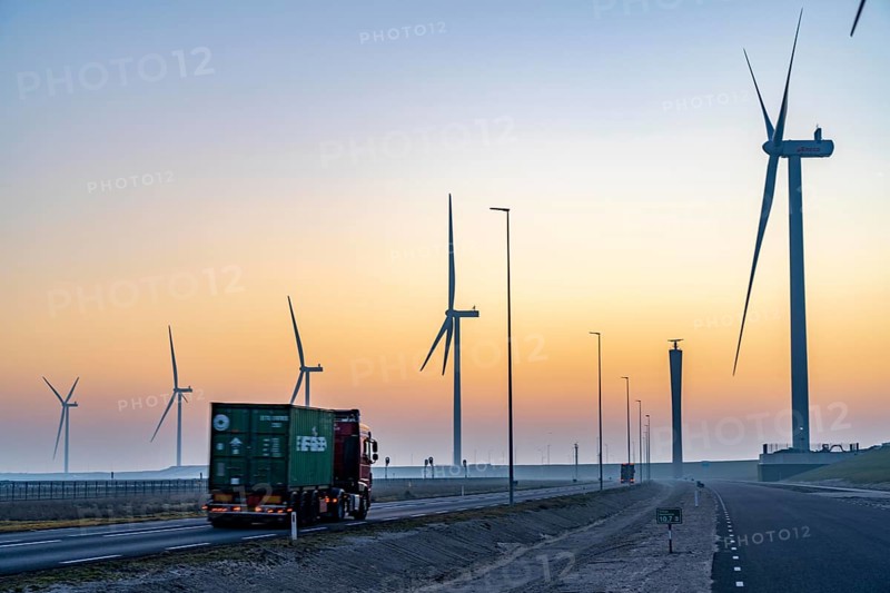 Lorry on the road from Euromax Terminal Rotterdam, ENECO wind farm on the dike around the port of Maasvlakte 2, 22 wind turbines with a capacity of 116 megawatts, sunset, Rotterdam, Netherlands