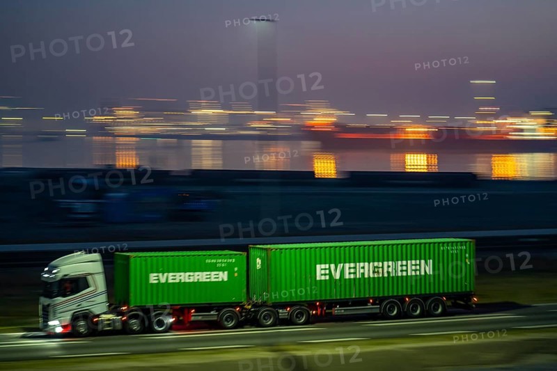 Lorry on the road to Euromax Terminal Rotterdam, ENECO wind farm on the dike around the port of Maasvlakte 2, 22 wind turbines with a capacity of 116 megawatts, sunset, Rotterdam, NetherlandsEvergreen Container