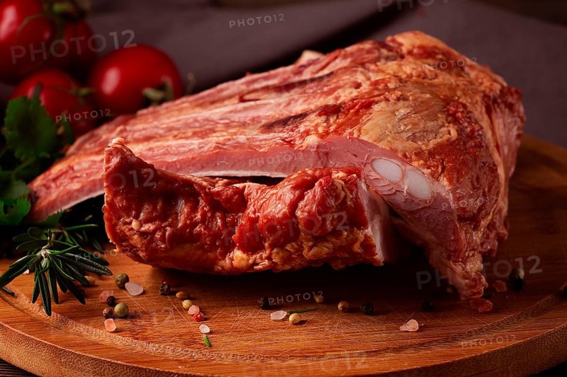Smoked pork ribs, on a wooden table, top view, sauce, tomatoes and spices, close-up, vertical, no people