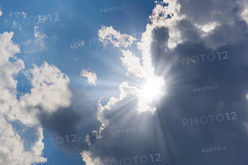 Rain clouds with sun shining through, rays of sunshine, blue sky