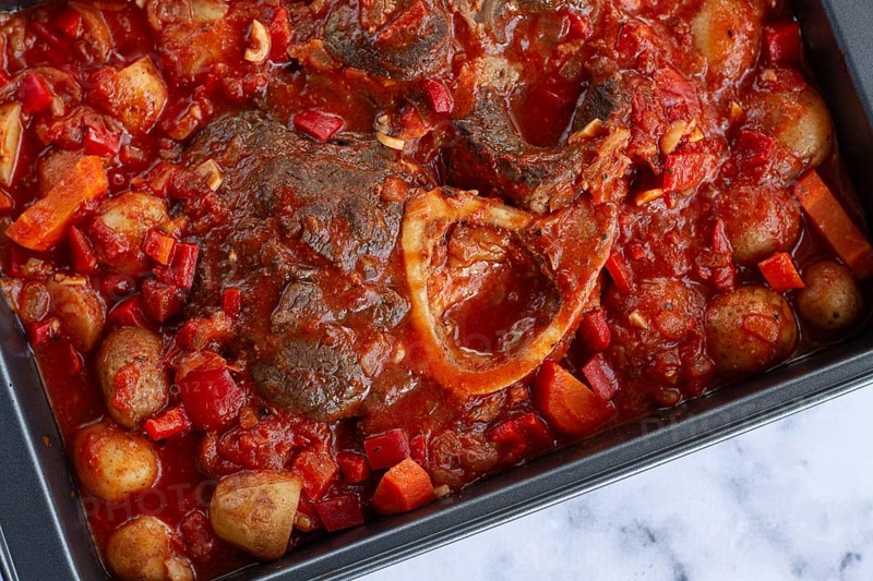 Ossobuco stew with vegetables, knuckle on the bone with new potatoes, in tomato sauce, homemade, top view, no people