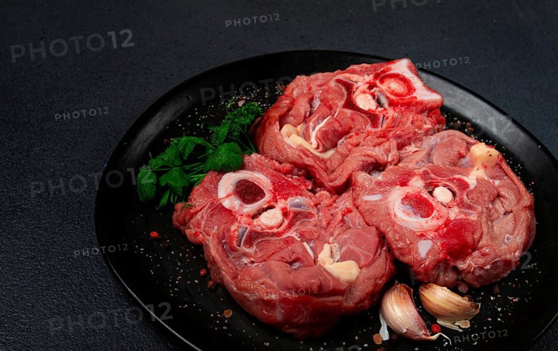 Raw steak, calf's neck on the bone, fresh meat, on a black plate, top view, no people