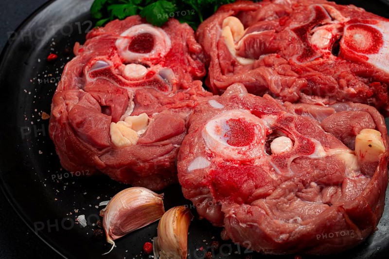 Raw steak, calf's neck on the bone, fresh meat, on a black plate, top view, no people