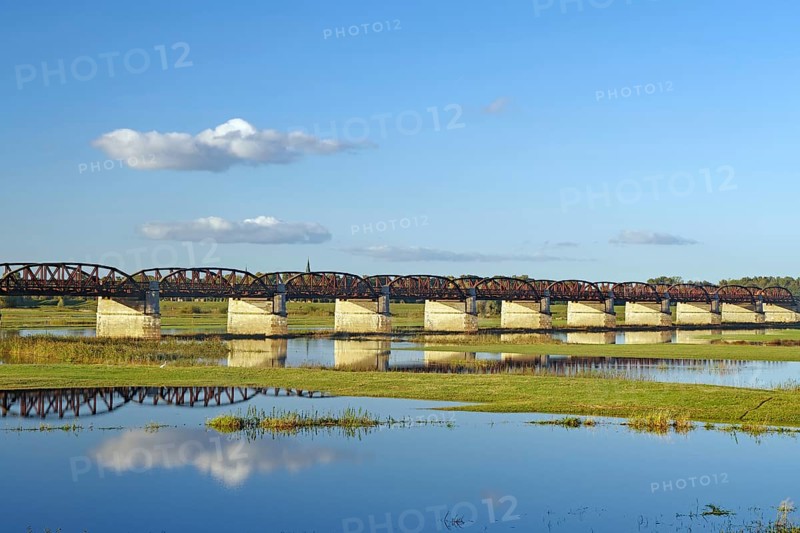 Long bridge over a calm river with reflections and green banks under a clear blue sky, autumn, Elbe, Dömitzer railway bridge, Langendorf, Wendland, Lower Saxony, Germany, Europe