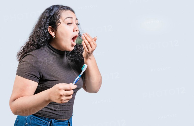Young woman holding brush with bad breath isolated. Person with brush and bad breath isolated, Person with halitosis