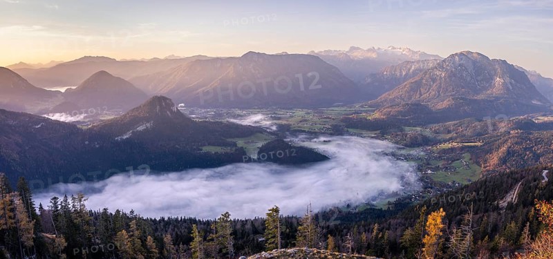 Panoramic photo: view from Mount Loser to Lake Altaussee, Altaussee, Bad Aussee, Tressenstein, Zinken, Sarstein, Dachstein mountains. Wafts of mist over the lake. In the morning at sunrise. Blue sky. Autumn, yellow larches. Altaussee, Bad Aussee, Ausseer Land, Totes Gebirge, Styria, Upper Austria, Austria, Europe