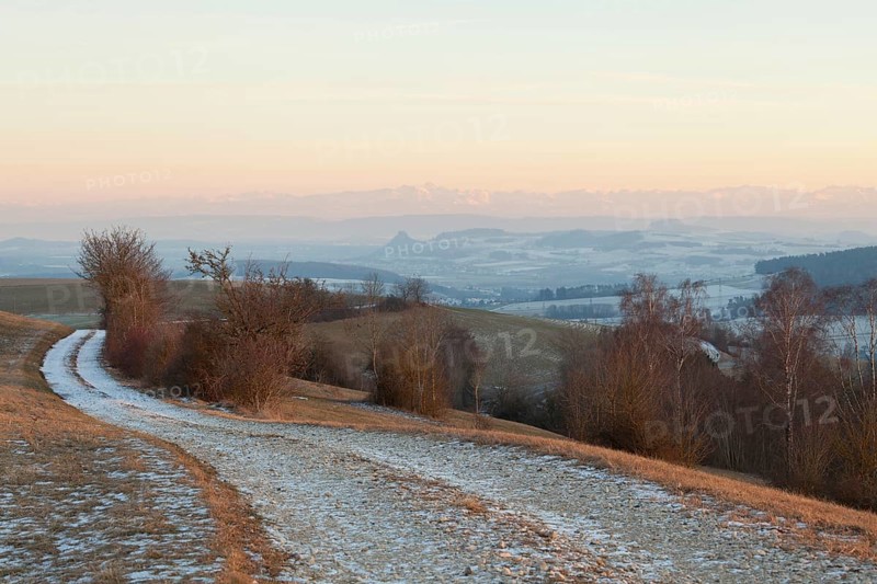Hegaublick in winter at sunset. Hohenkrähen castle ruins, Hohentwiel fortress ruins near Singen (Hohentwiel) with the Alps and the Säntis mountain