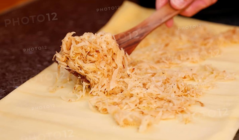 Swabian cuisine, preparation of Krautkrapfen, Swabian Mehlsäck, raw pasta pancakes filled with sauerkraut, savoury, salty, main course, grandmother's cooking, regional, home cooking, typical Swabian, traditional cuisine reinterpreted, man's hand, spatula, food photography, studio, Germany, Europe