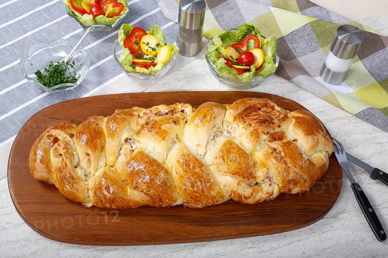 Swabian cuisine, hearty yeast plait with smoked meat, salty wreath bread, yeast yeast dough pastry, arranged on wooden board, baked, grandmother's kitchen, regional, home cooking, typical Swabian reinterpreted, traditional cuisine reinterpreted, salad in the back, small bowl, food photography, studio, Germany, Europe