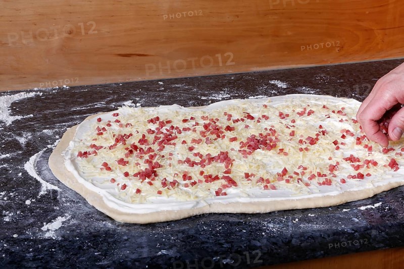 Swabian cuisine, preparation of savoury yeast plait with smoked meat, salty wreath bread, yeast yeast dough pastries, raw yeast dough sprinkled with diced bacon, grated cheese, sour cream, grandmother's cooking, regional, home cooking, typical Swabian cuisine reinterpreted, traditional cuisine reinterpreted, men's hands, food photography, studio, Germany, Europe