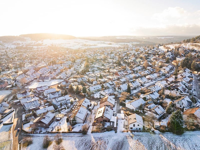 Snowy village in hilly landscape with winter sunlight over the fields, Calw- Stammheim, Black Forest, Germany, Europe
