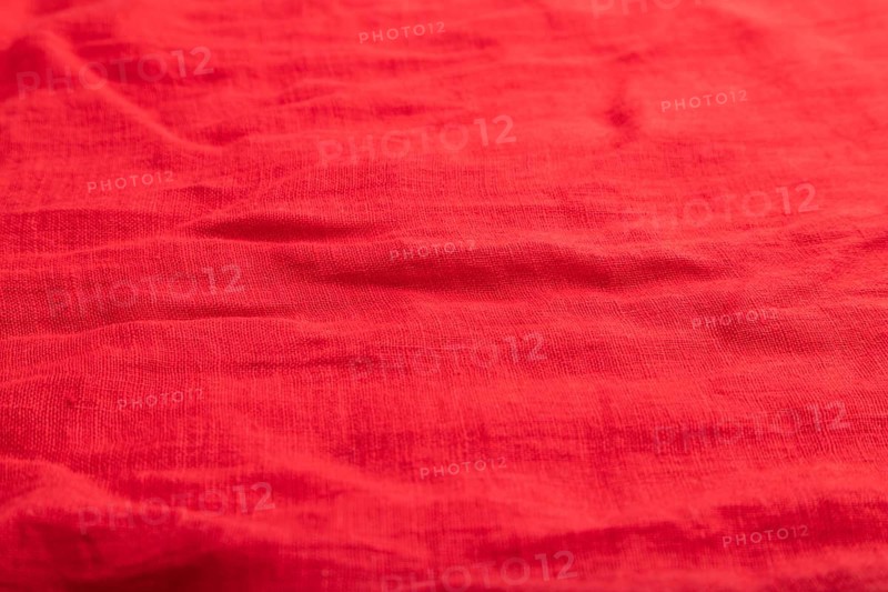 Fragment of smooth red linen tissue. Top view, flat lay, natural textile background and texture