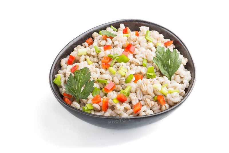 Pearl barley porridge with vegetables in blue ceramic bowl isolated on white background. Side view, close up. Russian traditional cuisine