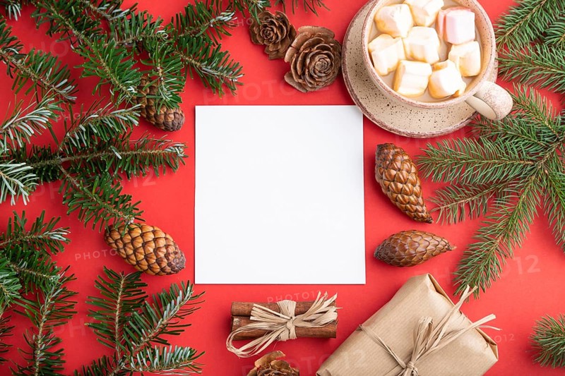 Christmas or New Year frame composition, template. Decorations, box, cinnamon, cones, fir and spruce branches, cup of coffee, on a red paper background. Top view, copy space, flat lay