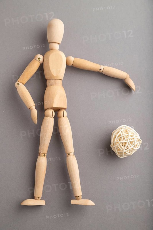Wooden mannequin playing football on gray pastel background. copy space, isolated, sports concept