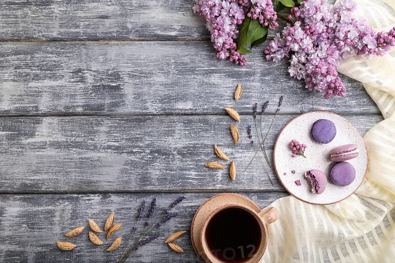 Purple macarons or macaroons cakes with cup of coffee on a gray wooden background and white linen textile. Top view, flat lay, copy space