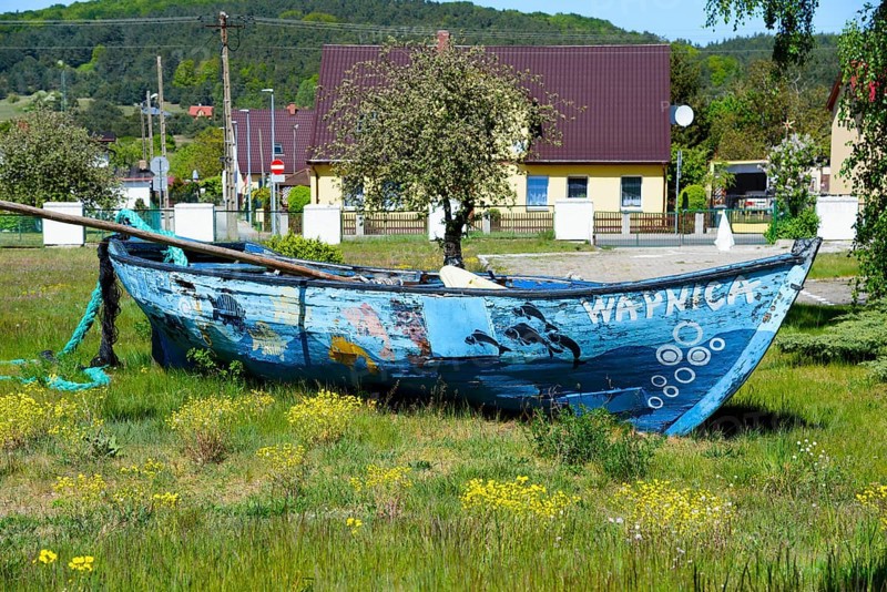 A weathered boat in a meadow with a village in the background, Wapnica, Wollin Island, Wolin, West Pomerania, Poland, Europe