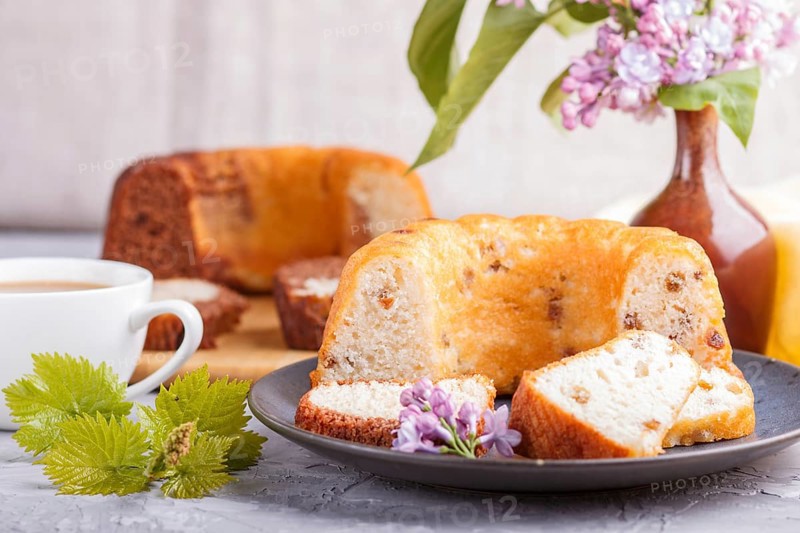 Cakes with raisins and chocolate and a cup of coffee. lilac flowers on a gray concrete background, side view