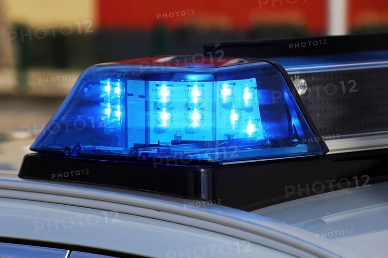 Symbolic image: Close-up of a police car with blue lights at night