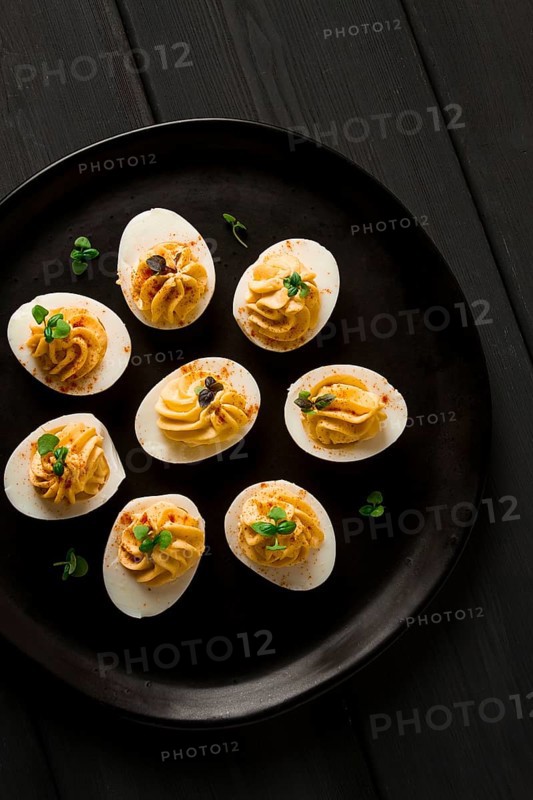 Boiled eggs stuffed with yolk with mayonnaise, on a black plate, selective focus, blurry, close-up, no people