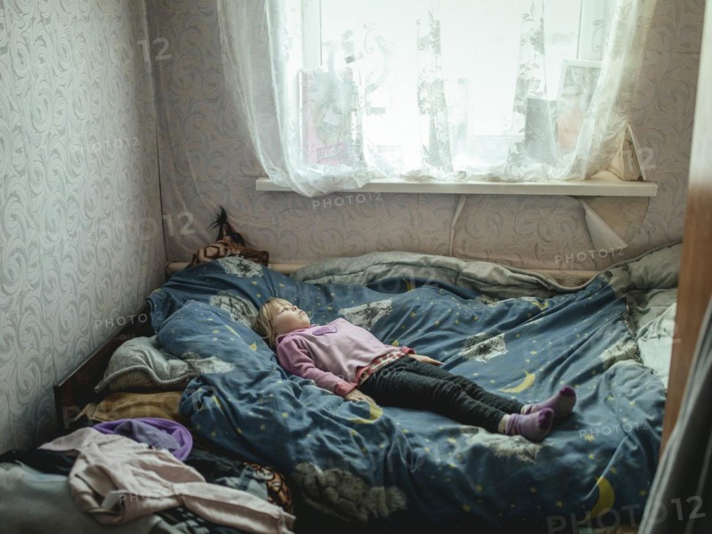 Angelina, 9 years old, on her bed. The village of Borshchivka was under Russian occupation. She has anxiety disorders. Angelina and her grandmother Larisa hid in their house for almost six months in Borshchivka, Raion Isyum, Kharkiv Oblast, Ukraine, Europe