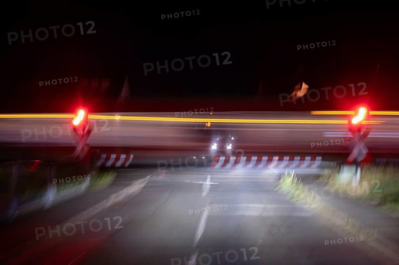 Passing train at a level crossing with barriers at night, Eckental, Middle Franconia, Bavaria, Germany, Europe