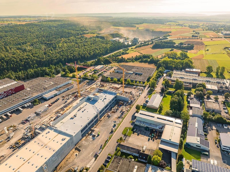 A bird's eye view of an industrial area with construction cranes and factory buildings, surrounded by trees and roads, Wolfsberg industrial area, Nagold, Black Forest, Germany, Europe