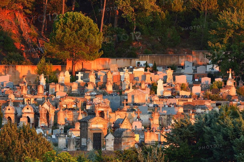A serene hillside cemetery with numerous tombstones bathed in the warm glow of a setting sun, Roussillon, Provence, Vaucluse, France, Europe