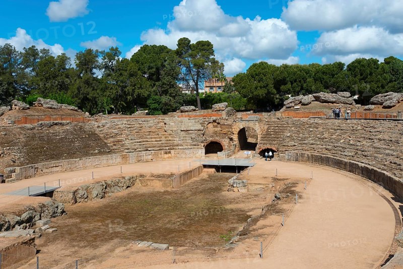 Partial view of a Roman amphitheatre with sandy floor and surrounding trees under a blue sky, Amphitheatre of Mérida, Merida, Badajoz, Extremadura, Spain, UNESCO World Heritage Site, Europe