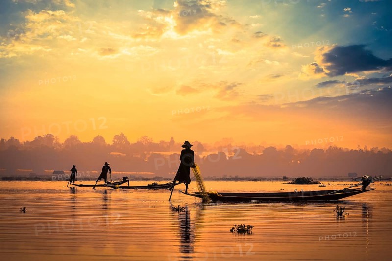 Myanmar travel attraction landmark, traditional Burmese fishermen sihouettes at Inle lake on sunset, Myanmar famous for their distinctive one legged rowing style