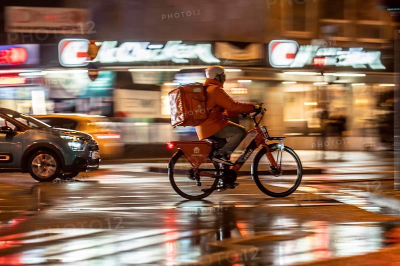 Street at the main station, Lieferando courier, cyclist, rainy weather, city centre, in the evening, Essen, North Rhine-Westphalia, Germany, Europe