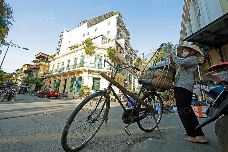 Vietnamese woman with conical hat prepares her bicycle for her sales tour through the Old Quarter, frog perspective, Hanoi, Vietnam, Asia