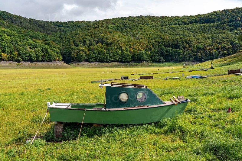 The Edersee, near Waldeck, the third largest reservoir in Germany, currently has only just under 13% of its normal level, the lake was last full in May 2022, dried up due to lack of rain, stranded fishing boat, rowing boat, the lake shore and the lake bottom is overgrown with fresh grass, Hesse, Germany, Europe
